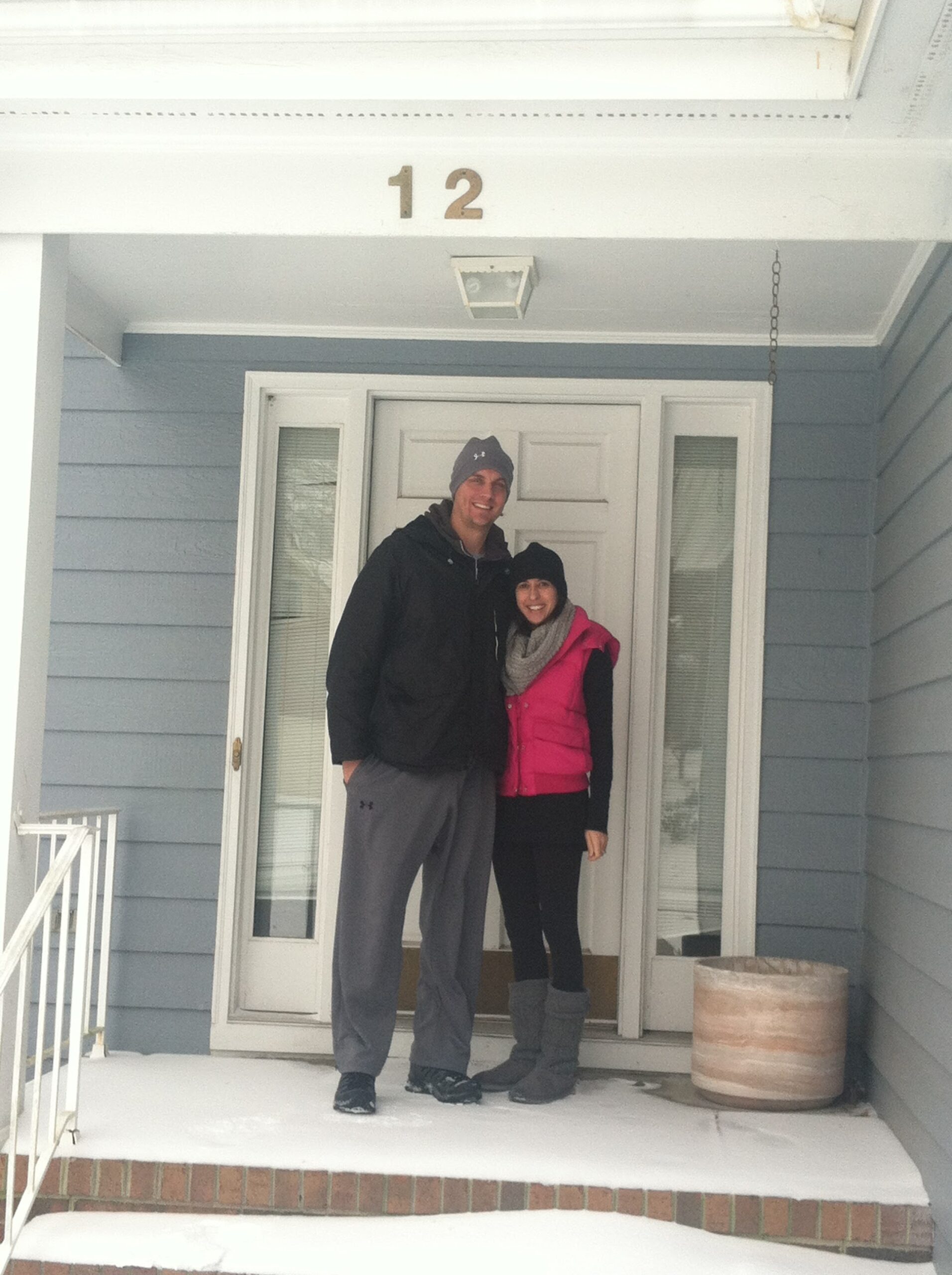 Young couple in front of house in the snow